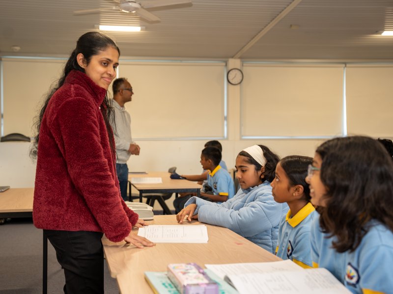 A teacher checking in with students at their desks