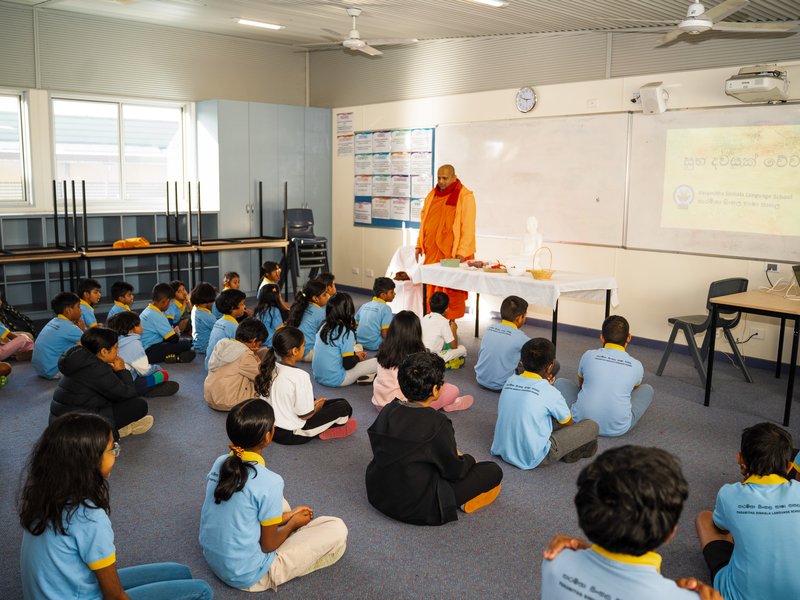 A monk teaching a full classroom of students