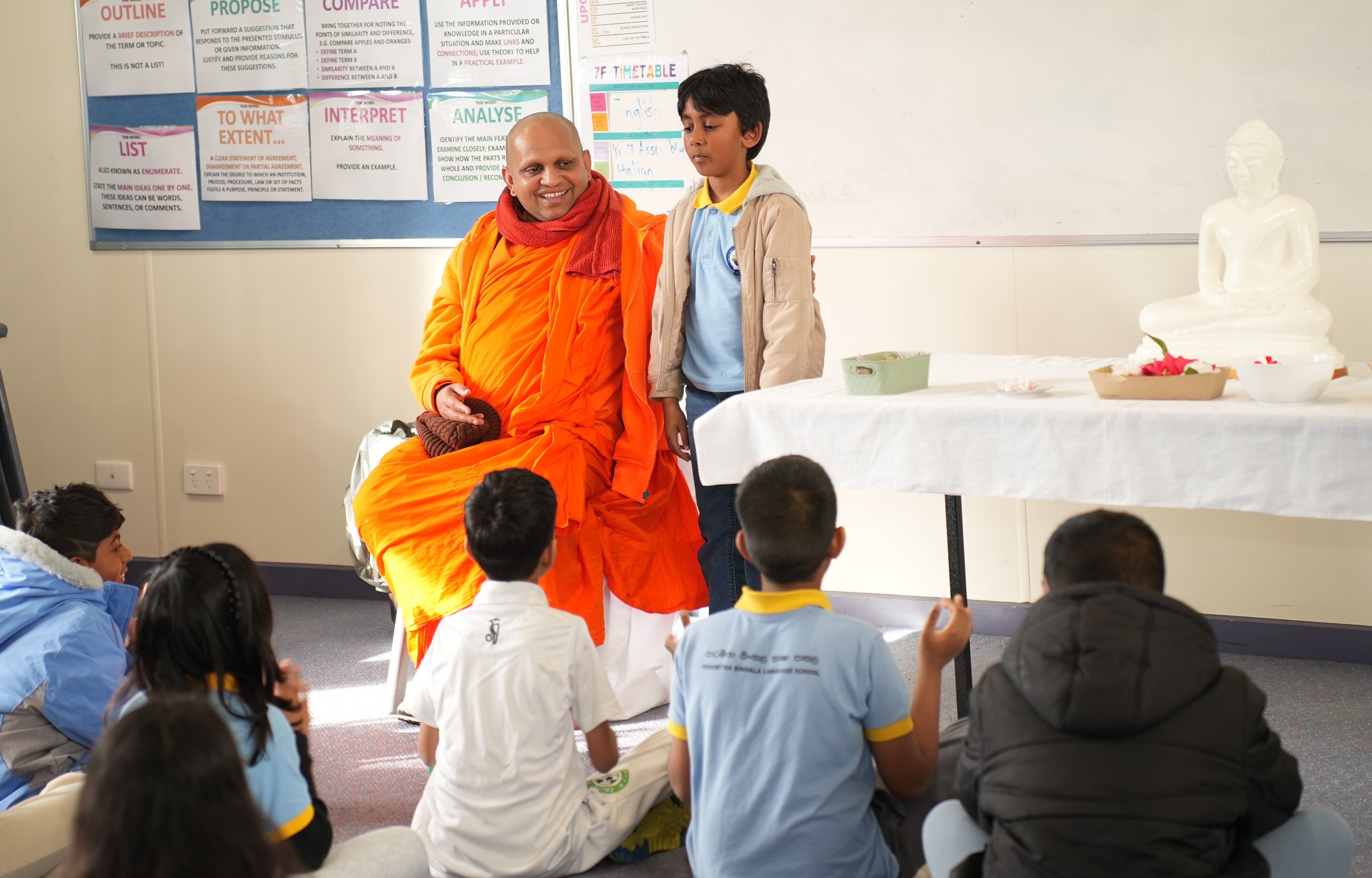 A teacher helping a student write Sinhala letters on the whiteboard